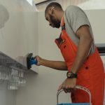 A Man In Gray Shirt Cleaning The Wall 6196687 150x150