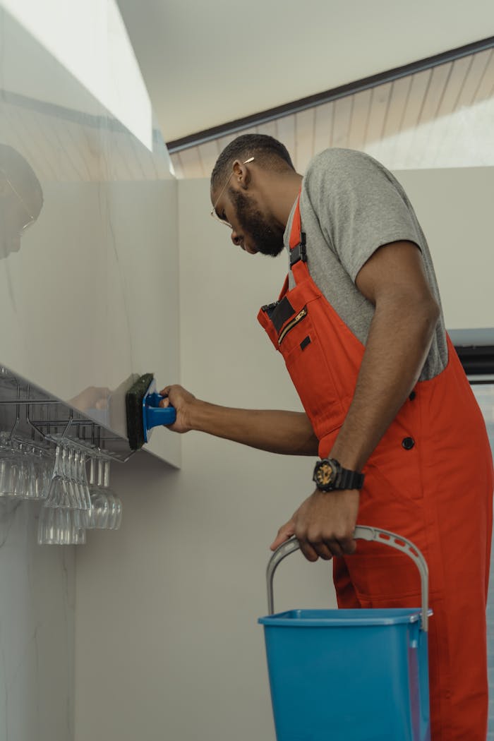 A Man In Gray Shirt Cleaning The Wall 6196687